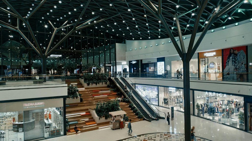 Explore a spacious and contemporary shopping mall featuring trendy shops, lush greenery, and stylish architecture.